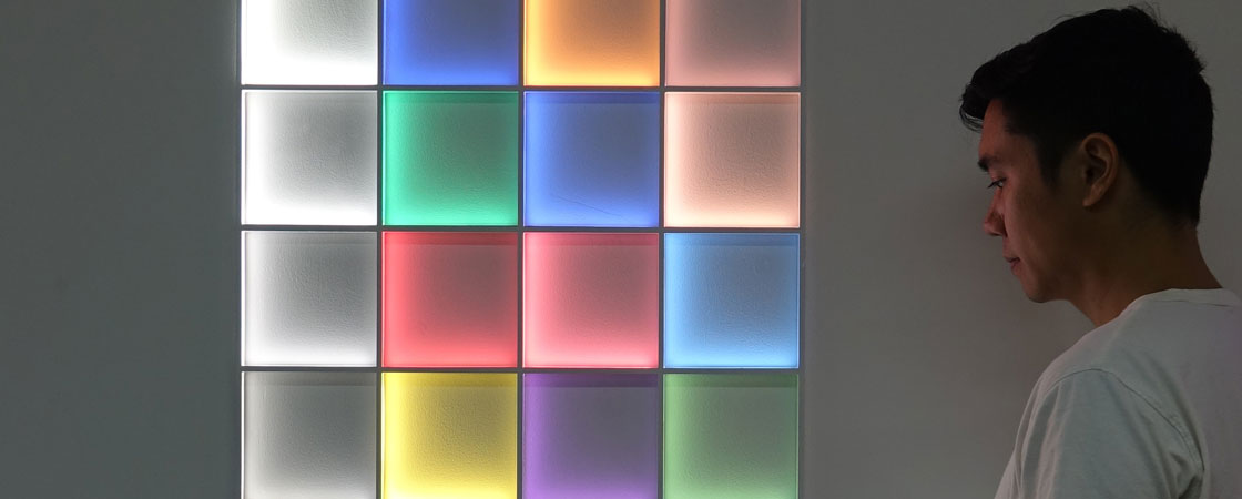 Man looking at colorful squares that are light up on a wall